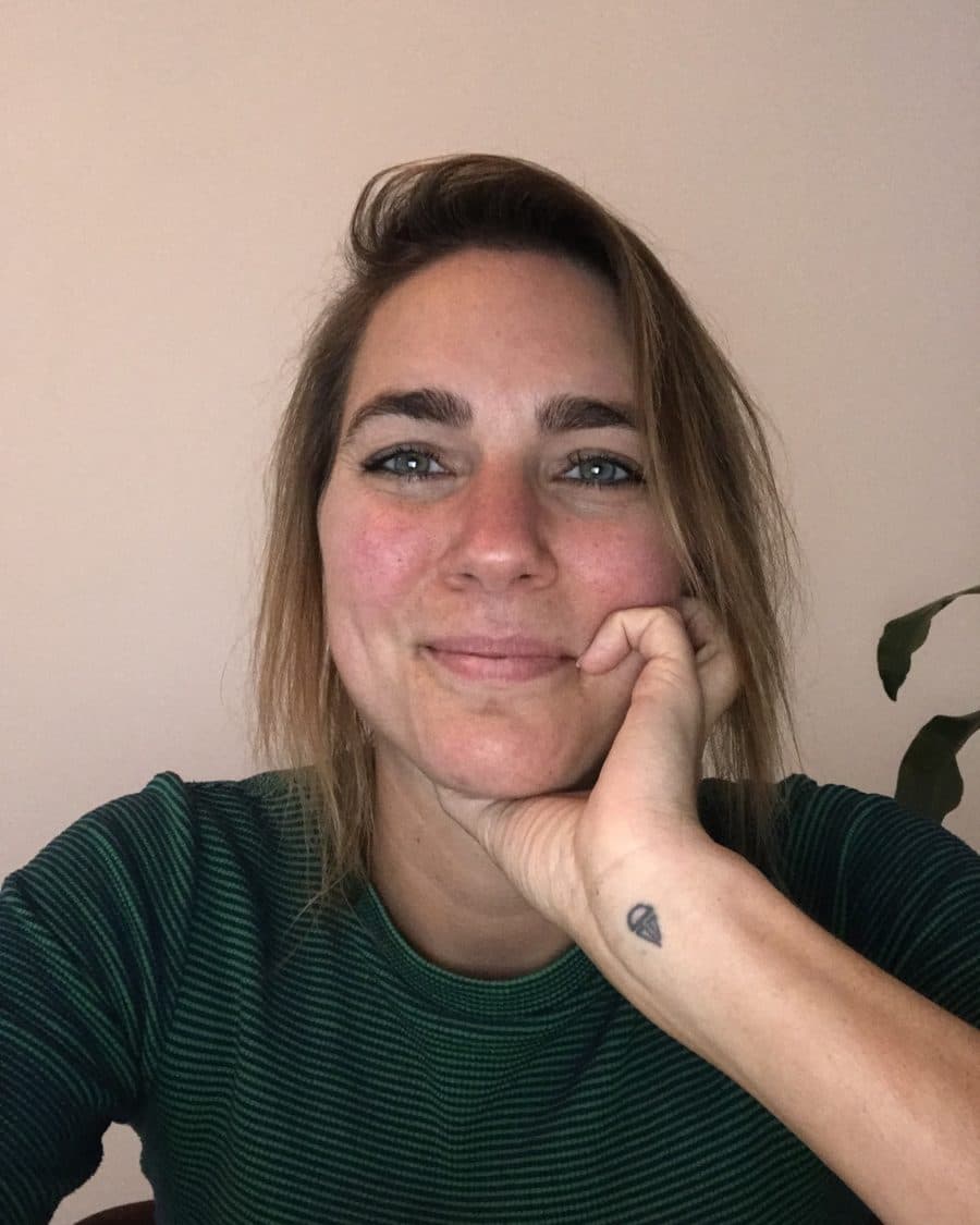 Janneke van den Brand, StudieKeuzeCoach in Amsterdam, met haar kin op haar hand voor een lichte muur