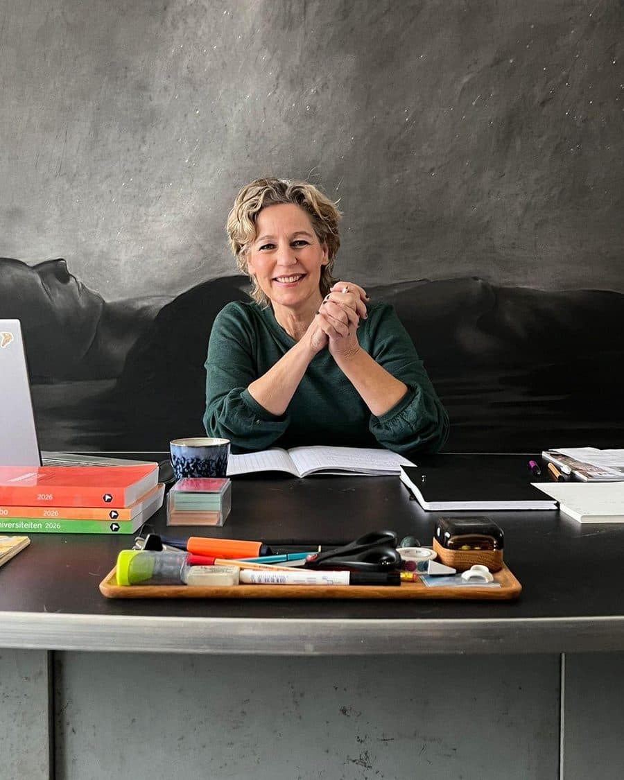 Regula Rexwinkel, StudieKeuzeCoach in Utrecht, aan haar werktafel met de Keuzegidsen voor mbo, hbo en universiteiten
